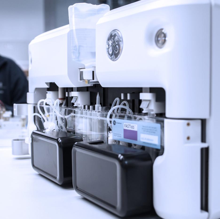 Nahaufnahme eines medizinischen Analysegeräts mit transparenten Röhren und schwarzen Verbrauchsmaterialien.