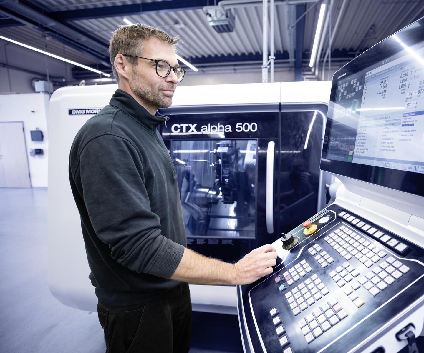 Ein Mann steuert eine CNC-Maschine CTX alpha 500 und betrachtet das Display mit Steuerungsinformationen.