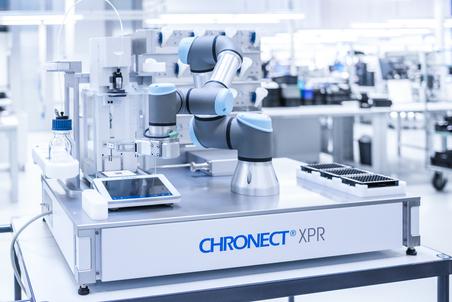 Nahaufnahme eines CHRONECT® XPR-Automationssystems mit einem Roboterarm und einer Pipette in einem Labor.