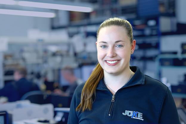 Elektronikmontage eine junge Elektronikerin steht in der Montage von Geräten und schaut lächelnd in die Kamera